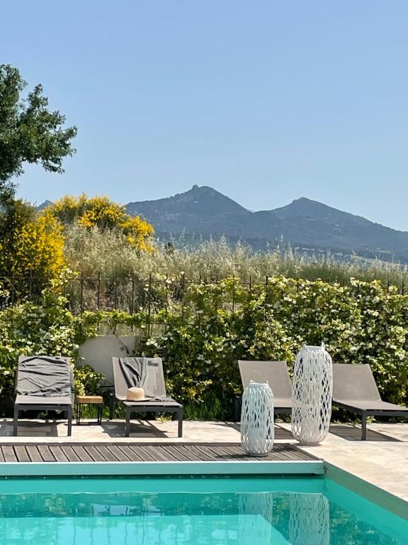 einen Pool mit Stühlen und Bergblick in der Unterkunft Le Mas Saint Philippe in Jonquières