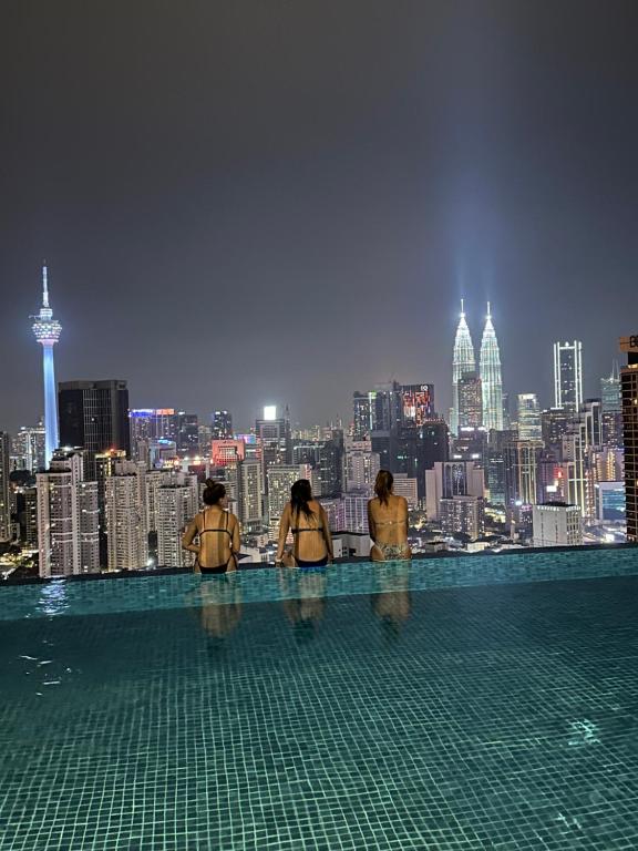 un grupo de personas de pie en el borde de una piscina con vistas a una ciudad en Lucentia residence T1, en Kuala Lumpur