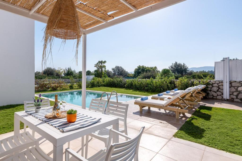 a patio with a table and chairs and a pool at New Brand Villas , Heating Pool , Jacuzzi , Spa near beach with children area ,2 min drive, beach, tavern,market in Haraki