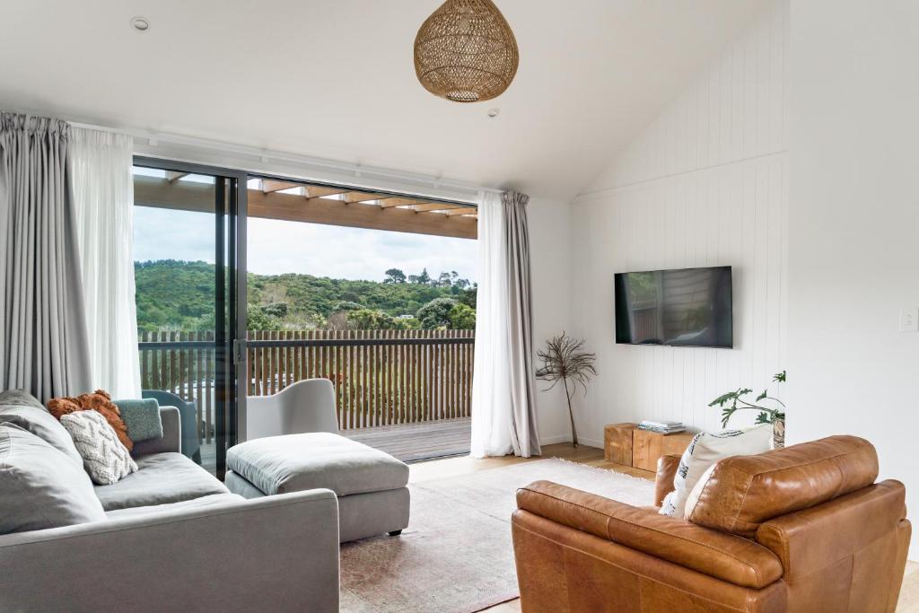 a living room with a couch and a tv at Wainui Landing Apartment 2 in Raglan