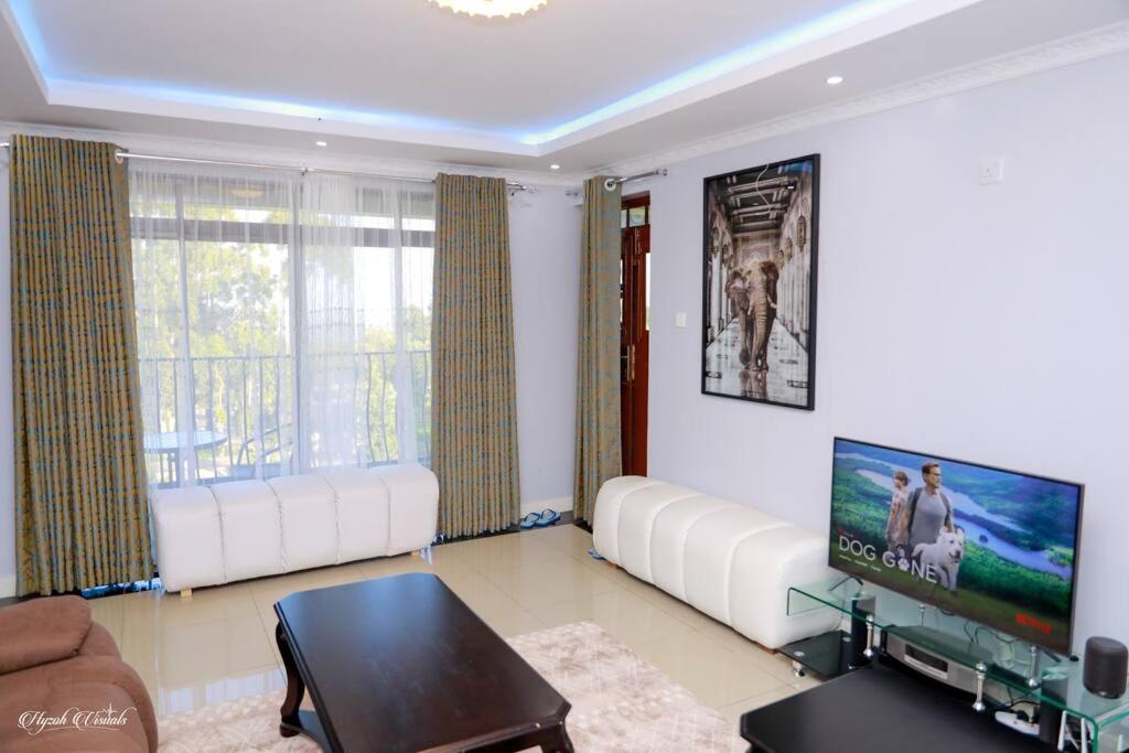 Il comprend un salon doté d'un mobilier blanc et d'une télévision à écran plat. dans l'établissement Luxe Furnished Premium Unit, à Meru