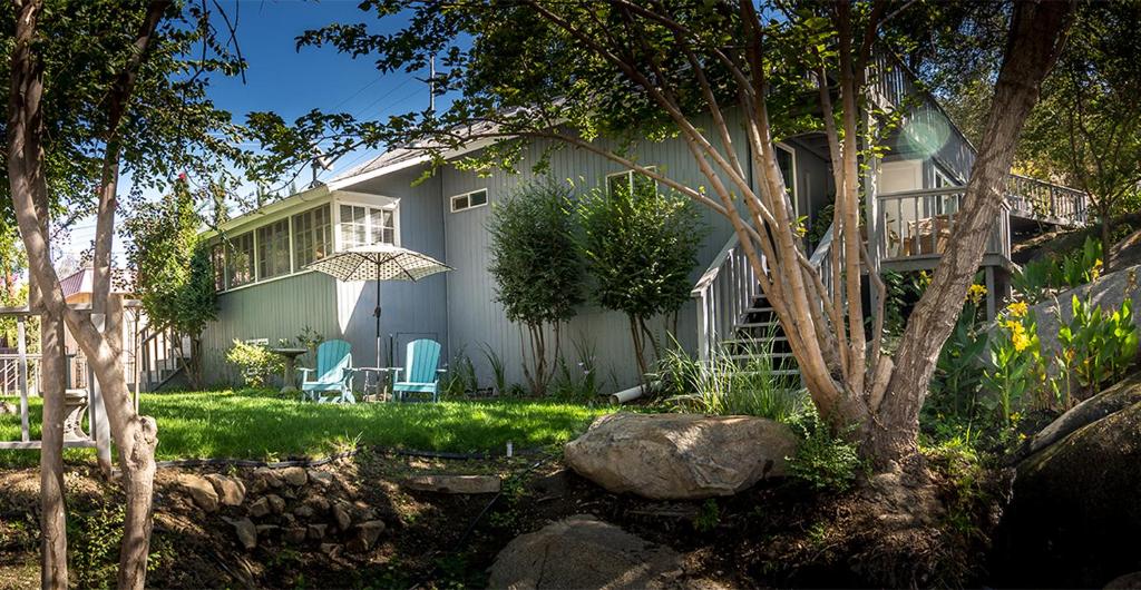 una casa con dos sillas y una sombrilla en el patio en Birdwatch Cottage With River Beach Pass, en Three Rivers