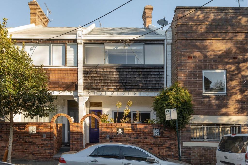 a brick house with a car parked in front of it at Sunny Apartment in Surry Hills in Sydney