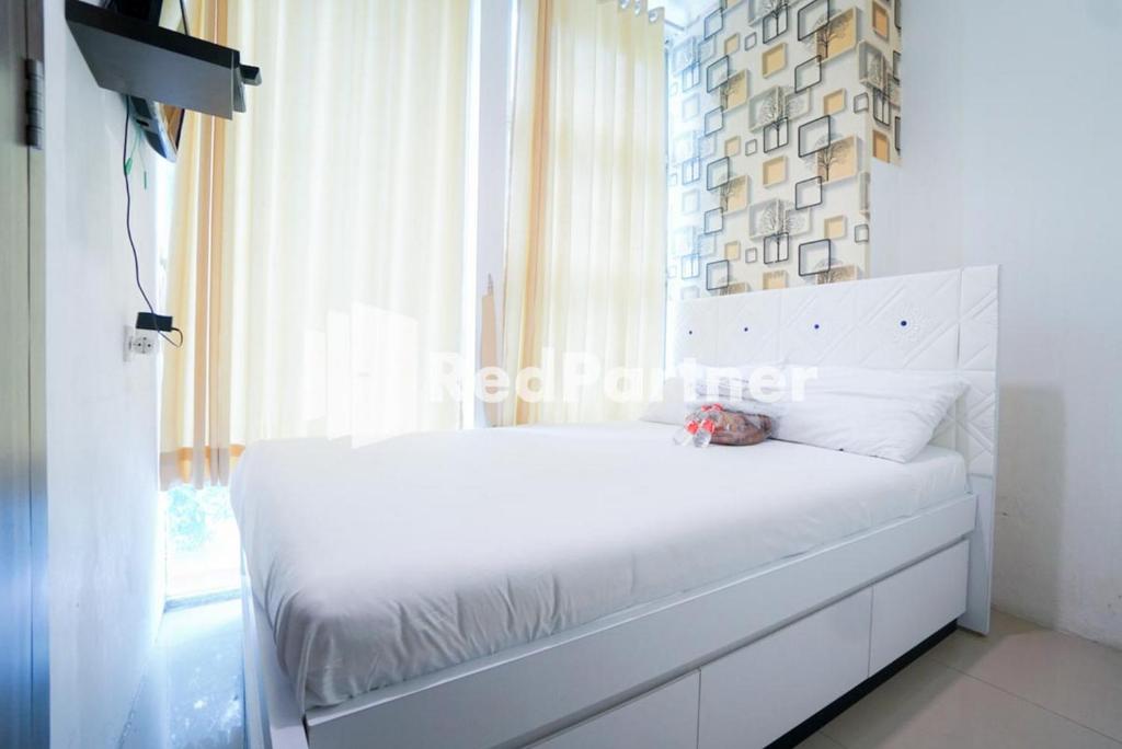 un letto bianco in una stanza con finestra di Eascot Hotel Mitra RedDoorz a Giacarta
