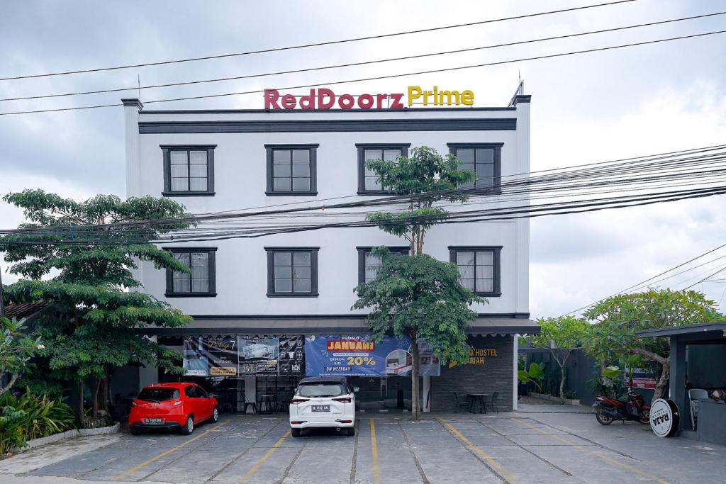 a white building with a red roof prime sign on it at RedDoorz Premium at Raja Hostel Syariah in Hajimana
