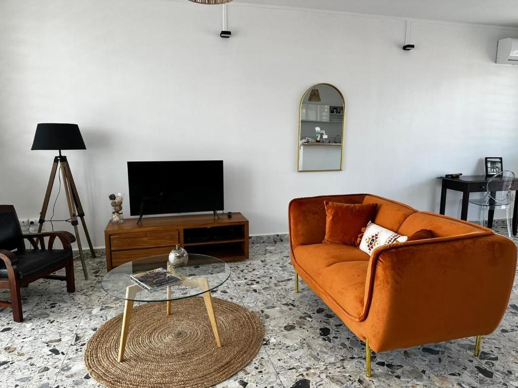 a living room with a orange couch and a table at Pomme Surette in Sainte-Anne