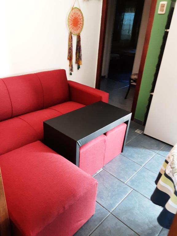 sala de estar con sofá rojo y TV en Apartamento a dos cuadras de Plaza de Toros y Rambla, en Colonia del Sacramento