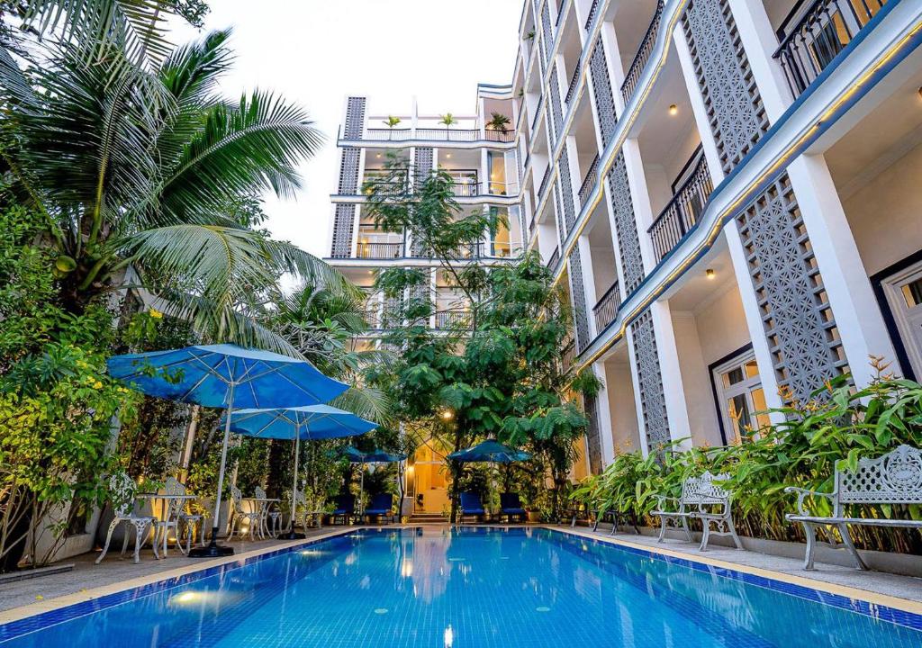 a swimming pool in a building with blue umbrellas at Kampot View Boutique in Kampot