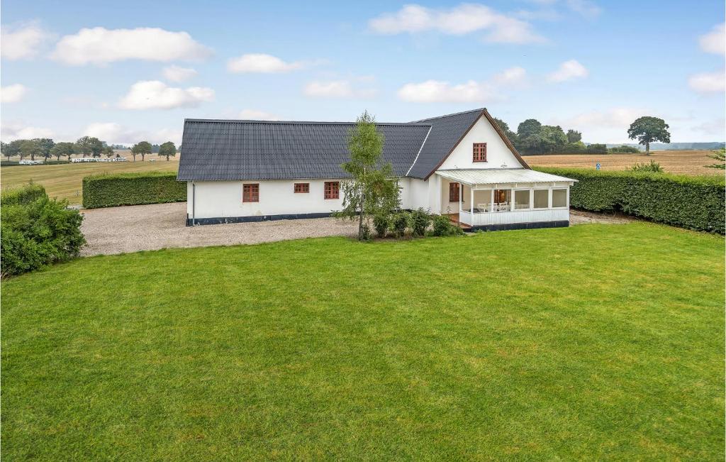 a white house with a large grass yard at Nice Home In Kvrndrup With 6 Bedrooms And Wifi in Kværndrup