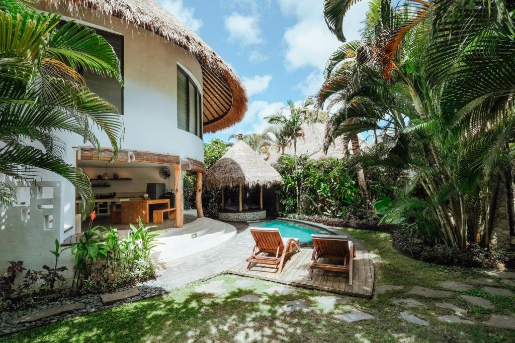 a villa with a swimming pool and palm trees at Barrels at Bingin in Uluwatu