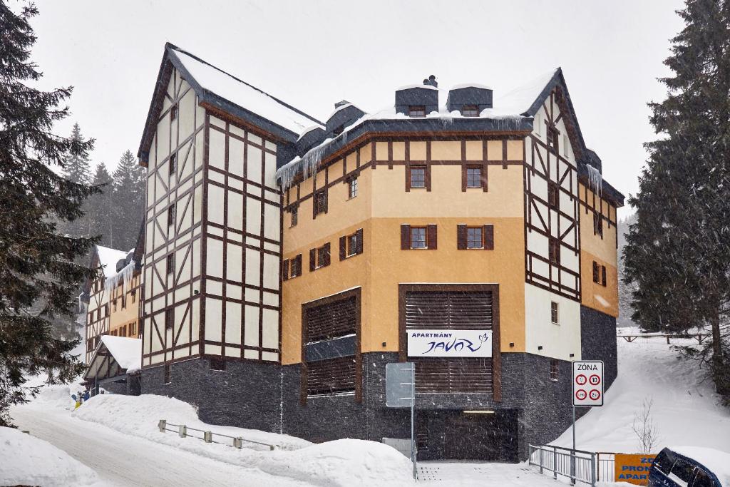a building in the snow with a sign in front of it at Apartmán u vleku Javor in Pec pod Sněžkou