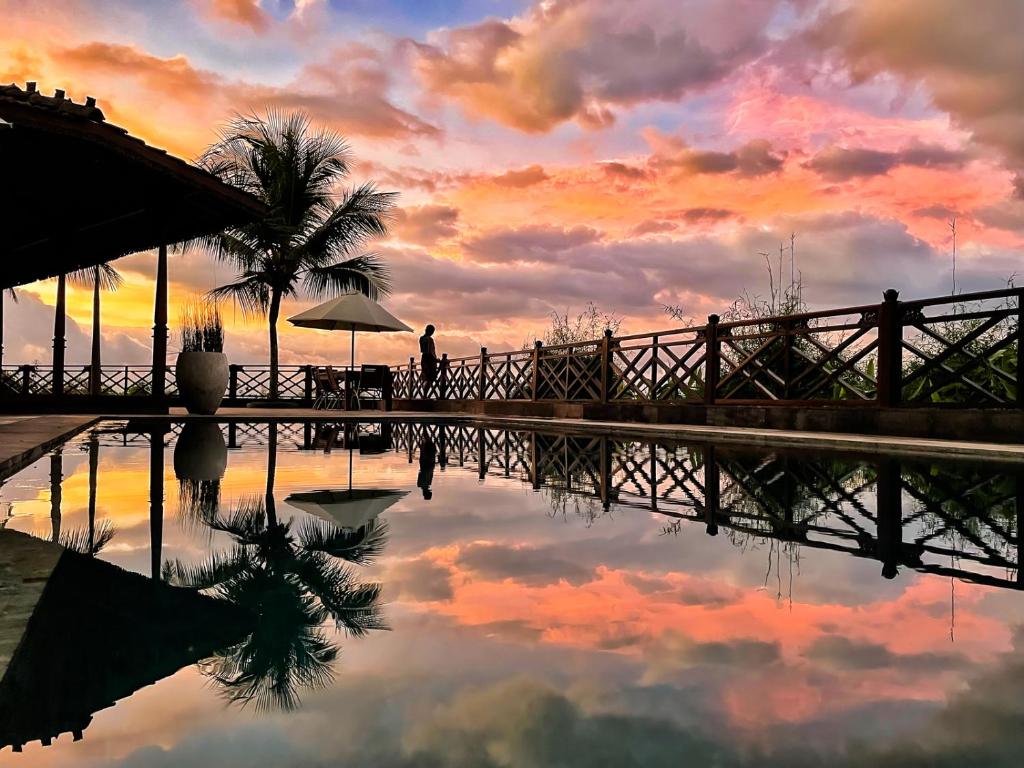 a reflection of a sunset in a pool of water at Villa Borobudur Resort in Borobudur