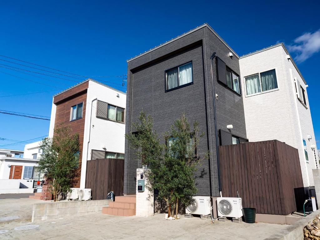 un edificio blanco y negro con árboles delante en Ocean Front Maezato, en Ishigaki Island