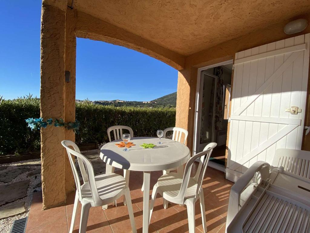 - une table et des chaises blanches sur la terrasse avec vue dans l'établissement Appartement 2 pièces cabine, piscine, tennis et parking sécurisé aux Issambres - FR-1-226-477, à Roquebrune-sur Argens