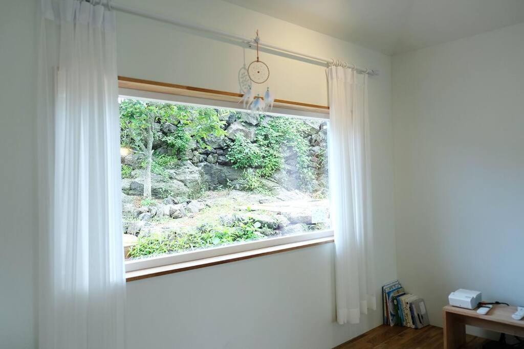 a window with white curtains in a room at That space Jeju in Jeju