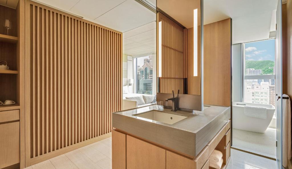 un bagno con lavandino, water e finestra di AKI Hong Kong - MGallery a Hong Kong