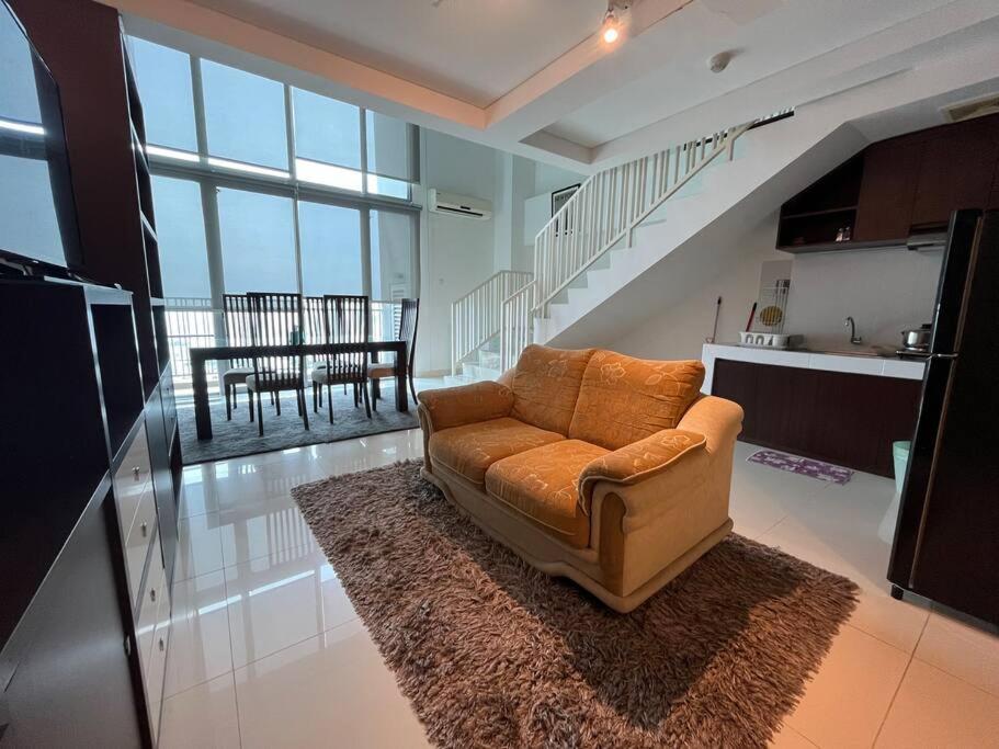 a living room with a couch in the middle of a kitchen at Neo Soho Apartment / Office near Central Park Mall in Jakarta