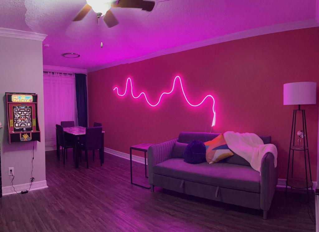 una sala de estar con una pared púrpura con un letrero de neón en Cozy houston Getaway 1 bed 1 bath, en Houston