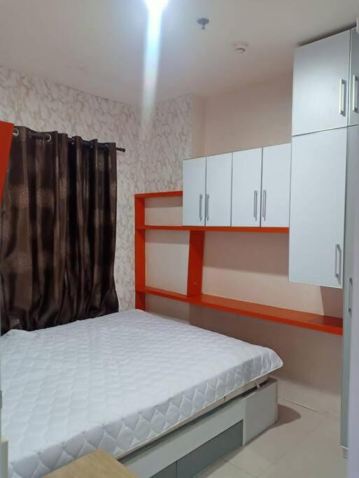 um pequeno quarto com uma cama e armários brancos em Comfort 2BR green pramuka bougenvile em Jakarta