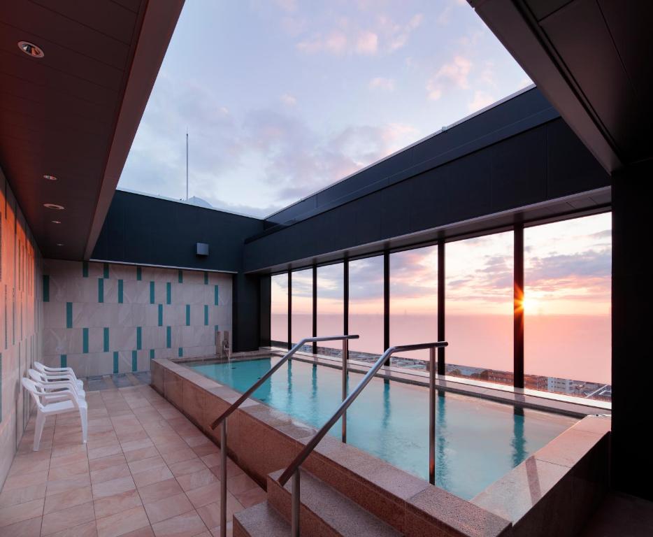 a pool in a building with a view of the ocean at Candeo Hotel Utsunomiya in Utsunomiya