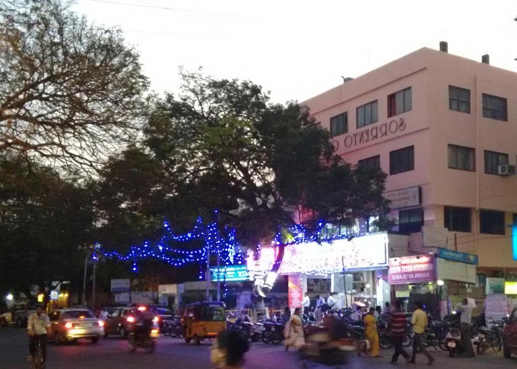 une rue urbaine animée avec un bâtiment aux lumières de Noël dans l'établissement Hotel Sorrento Guest house Anna Nagar East Metro Shenoy Nagar metro budget monthly daily rooms, à Chennai