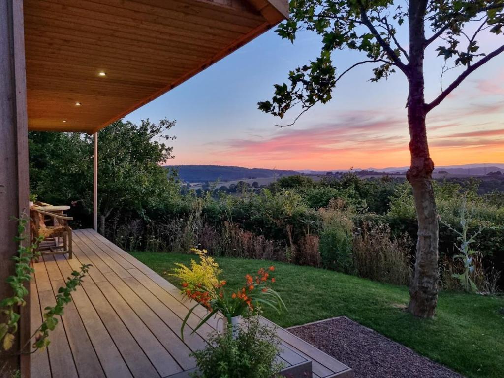 a wooden deck with a view of the sunset at Yartleton Farm in Aston Ingham