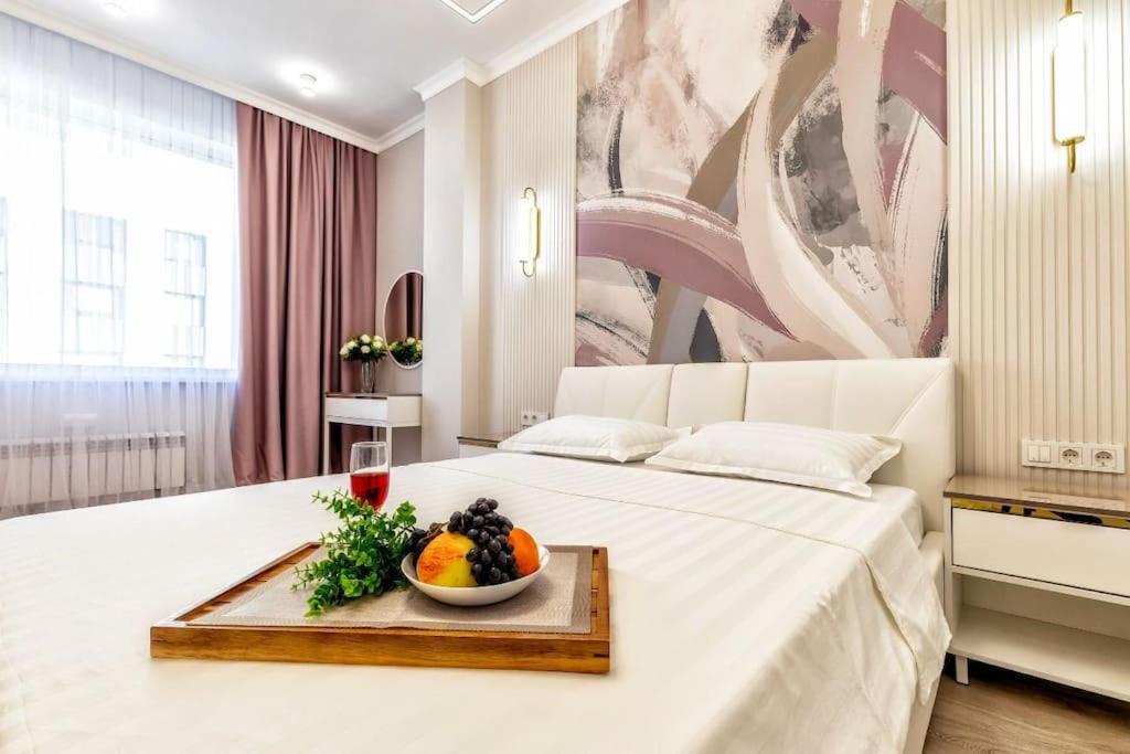 um quarto com uma cama branca e uma taça de fruta numa bandeja em Двухкомнатные аппартаменты Вдохновение в центре столицы em Astana