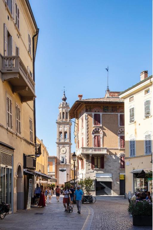 a group of people walking down a street with a clock tower at HOUSE Cavour 24 In the heart of Downtown Parma in Parma