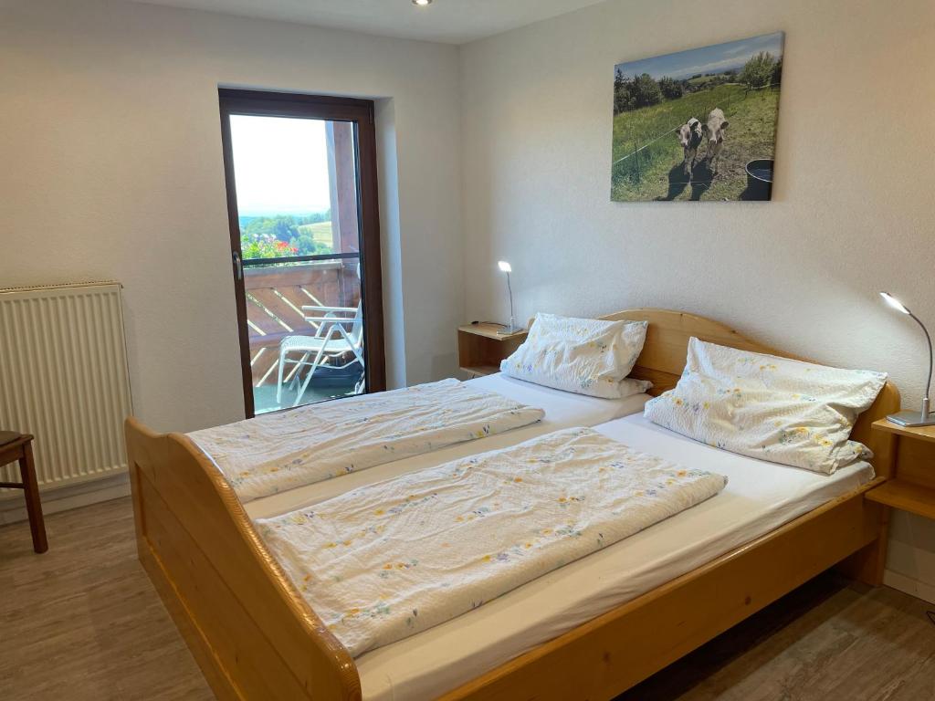 a large bed in a bedroom with a large window at Blumenhof - ERHOLUNG PUR, traumhafte Aussicht in Zell im Wiesental