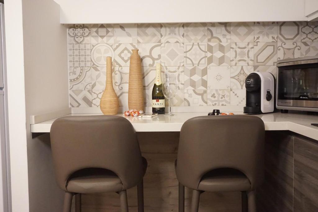 een keuken met een aanrecht met 2 stoelen en een tafel met wijnflessen bij Catanese Proverb's House - Via Napoli in Catania