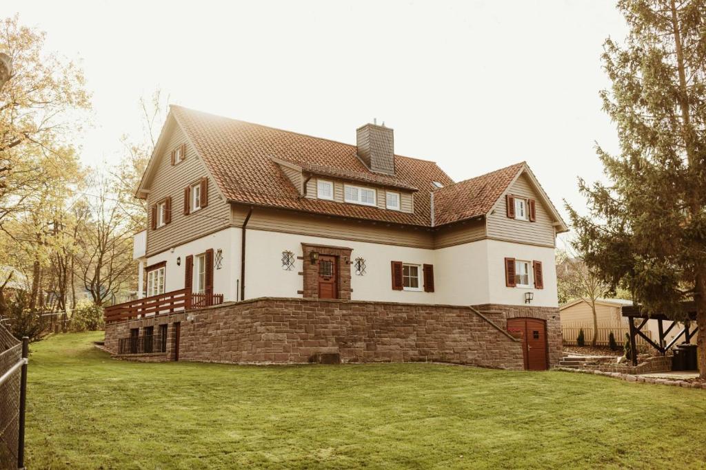 een groot wit huis met een bruin dak bij Waldchalet Am Steinberg in Wernigerode