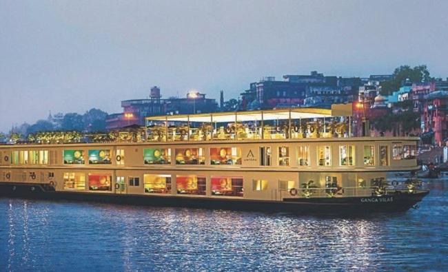 una grande nave da crociera sull'acqua con edifici sullo sfondo di Sankardev Guest House D24 35 a Varanasi