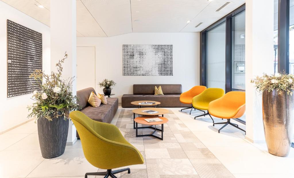 a lobby with yellow chairs and a couch and tables at Hotel Katharinenhof COMFORT in Dornbirn