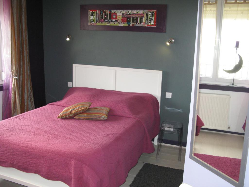 a bedroom with a pink bed with two pillows on it at Les Chambres de l&#39;Ile in Metz