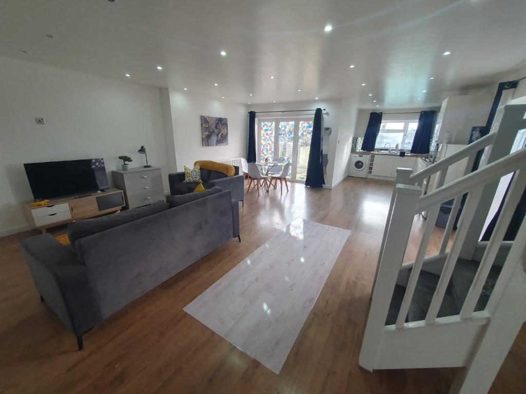 uma sala de estar com um sofá e uma televisão em Luxury 5 - Spacious Contractor's Delight with 4 Bedrooms and Ample Driveway Parking em Luton