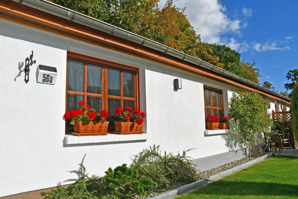 a white house with red flowers in windows at Ferienwohnung an der Granitz in Ostseebad Sellin