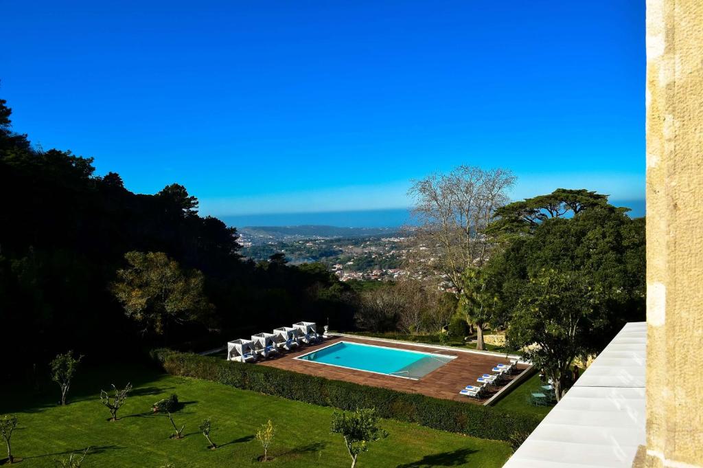 a swimming pool in a garden with chairs and a view at Tivoli Palácio de Seteais Sintra Hotel - The Leading Hotels of the World in Sintra