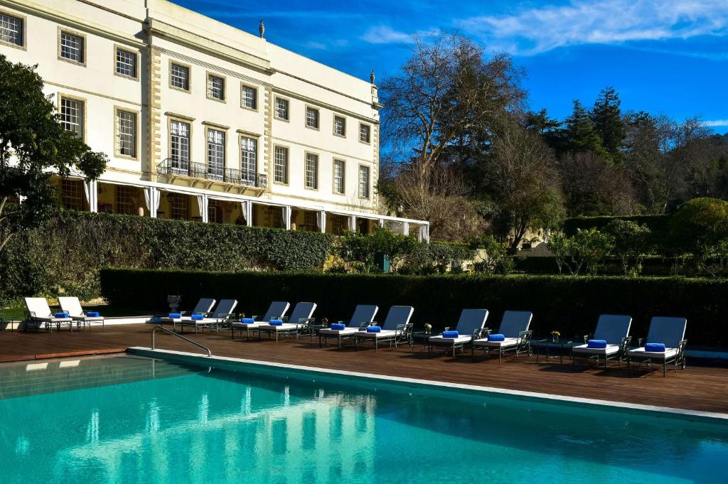 a row of lounge chairs next to a swimming pool at Tivoli Palácio de Seteais Sintra Hotel - The Leading Hotels of the World in Sintra