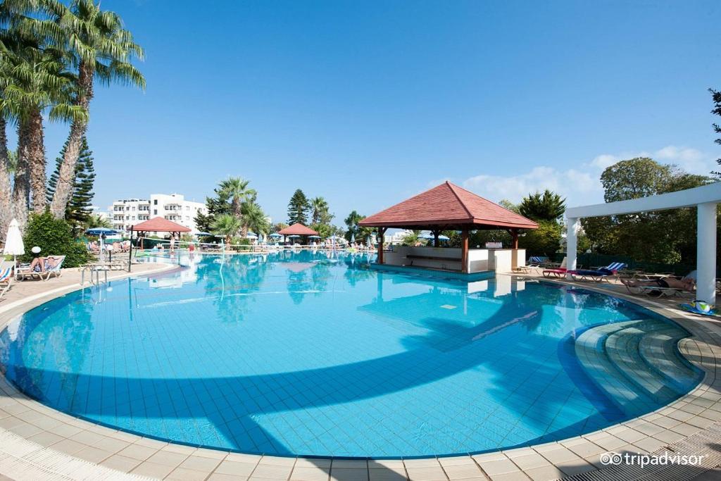 a large blue swimming pool with a gazebo at Antigoni Hotel in Protaras