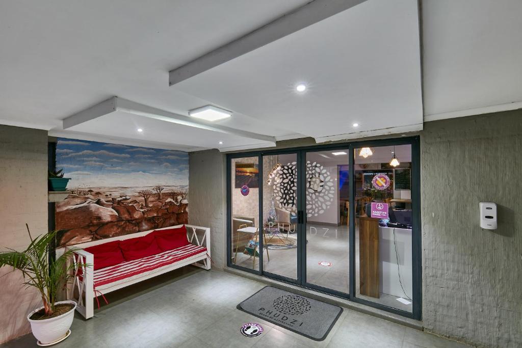 een kamer met een rode bank en een schilderij aan de muur bij Phudzi Hotel in Letlhakawe