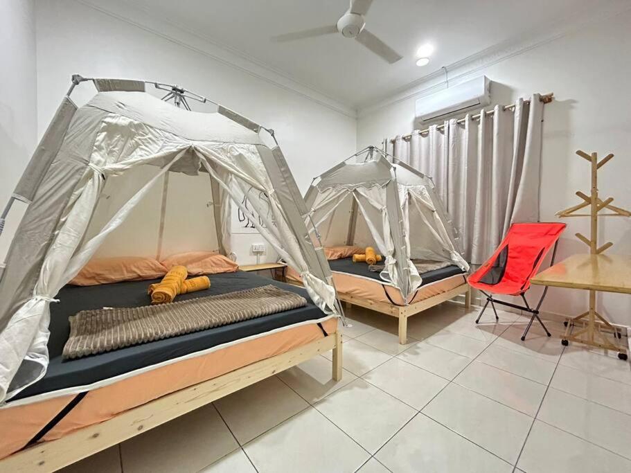 two beds in a room with a table and a red chair at Home of Camper 659 in Seremban (16-18Pax) in Seremban