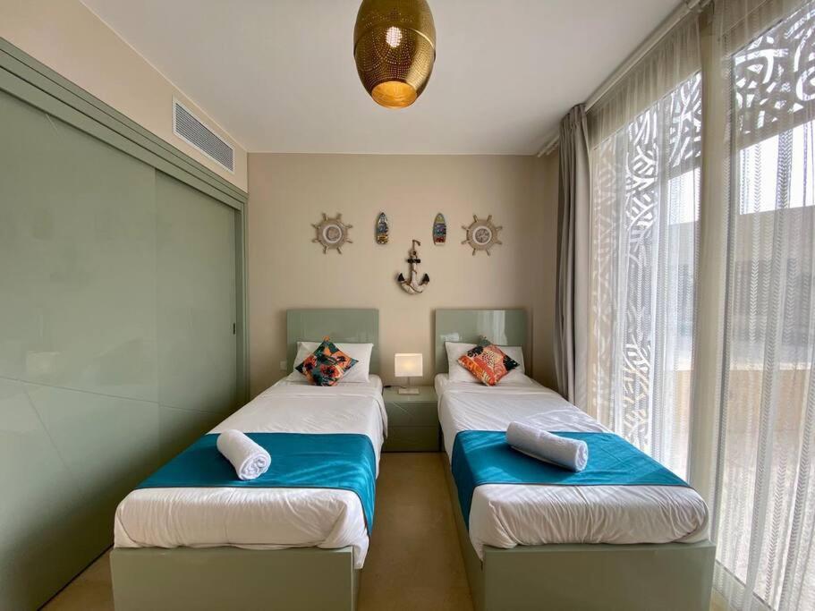 2 Einzelbetten in einem Zimmer mit Fenster in der Unterkunft Mangroovy - Buena Vista Pool and Marina views in Hurghada