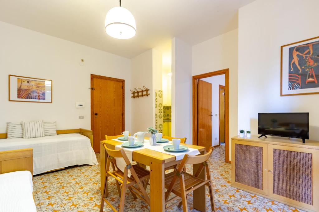 ein Wohnzimmer mit einem Tisch, Stühlen und einem TV in der Unterkunft Appartamento La Poesia Bilo 2 - MyHo Casa in Tortoreto Lido