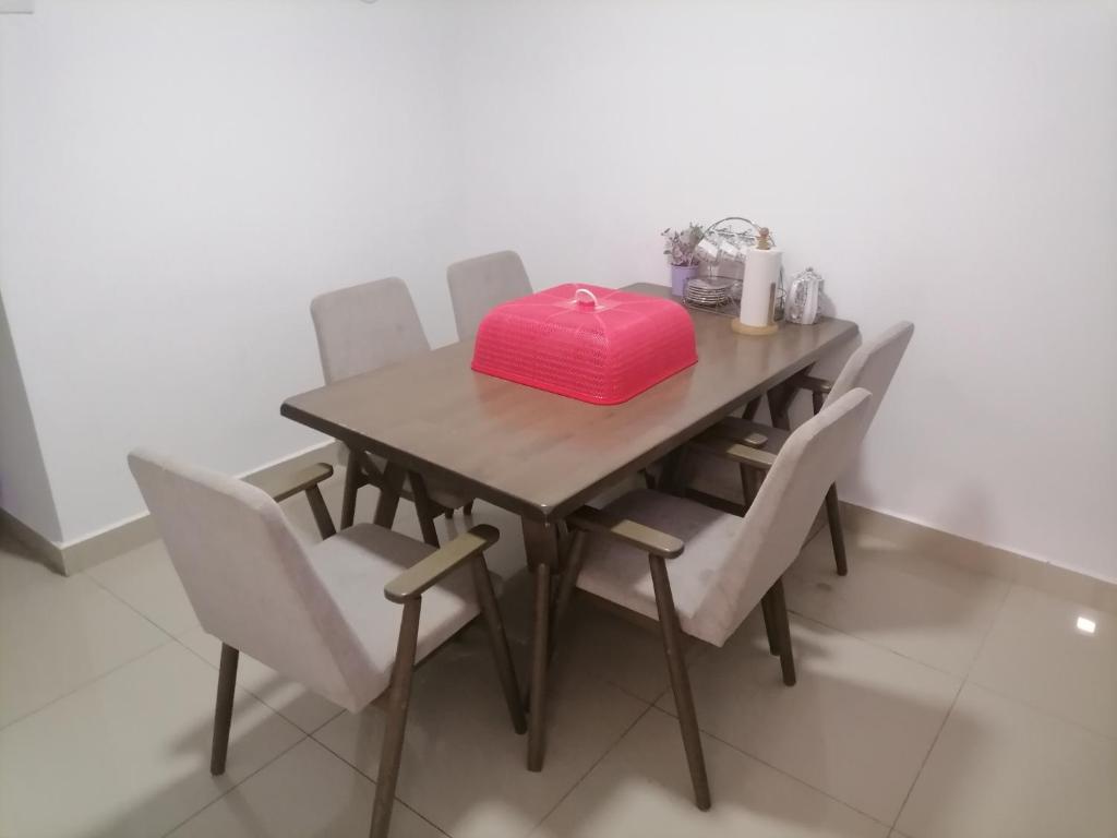a wooden table with white chairs and a pink box on it at D'Indah59 KLIA Homestay in Sepang