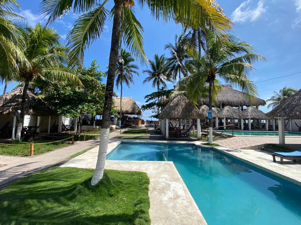una piscina con palmeras y cabañas en Hotel Paseo del Sol, en La Paz