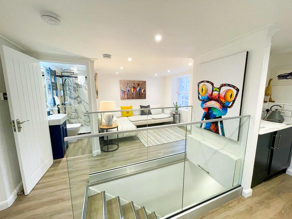 una sala de estar con una escalera de cristal en una casa en Stunning Loft Apartment South Queensferry High St Bridge Views!, en Queensferry
