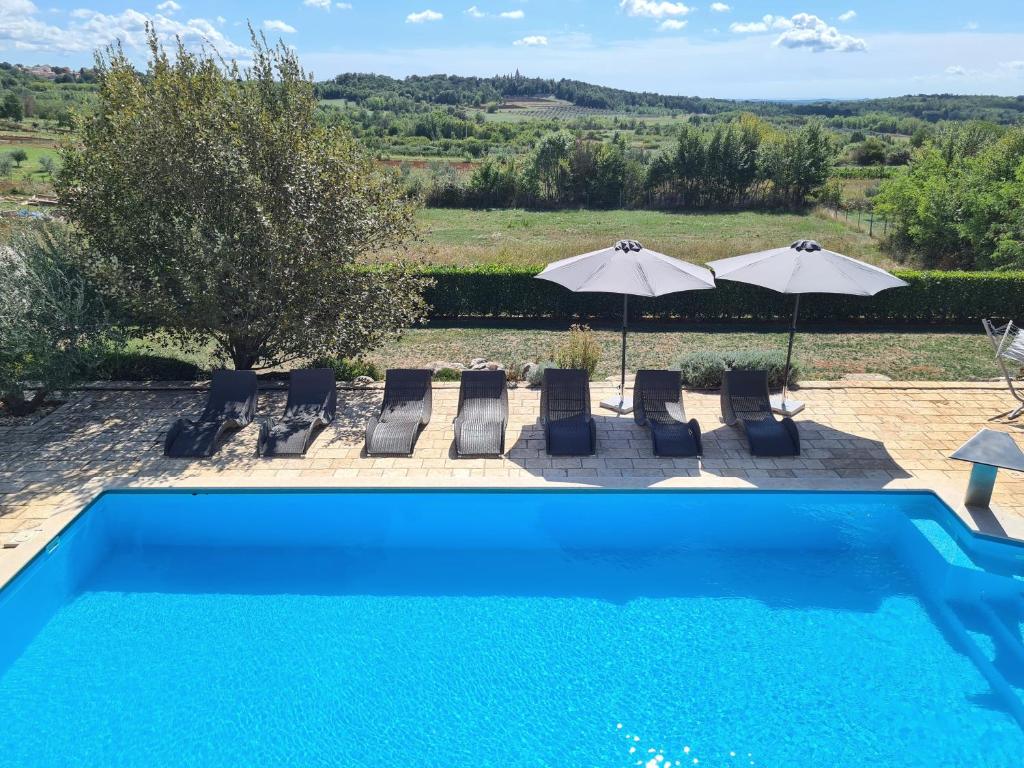 a swimming pool with chairs and umbrellas in a yard at Villa Stella - Gourmet Breakfast, Wellness & Pool in Višnjan