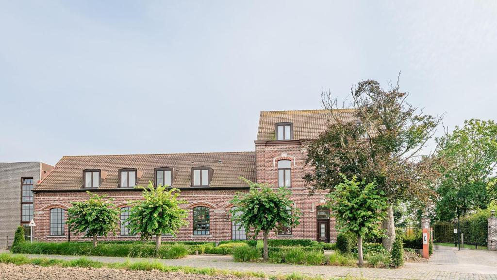 un gran edificio de ladrillo con árboles delante de él en Hotel De Pupiter, en Kluisbergen