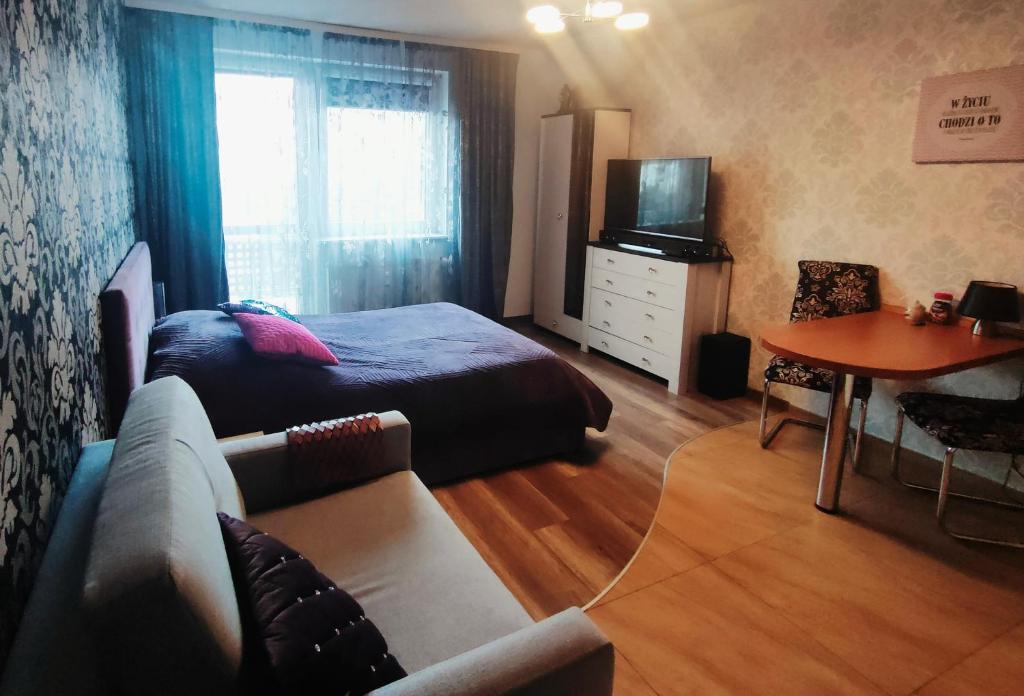 a bedroom with a bed and a couch and a table at Apartament Klonowa in Kołobrzeg