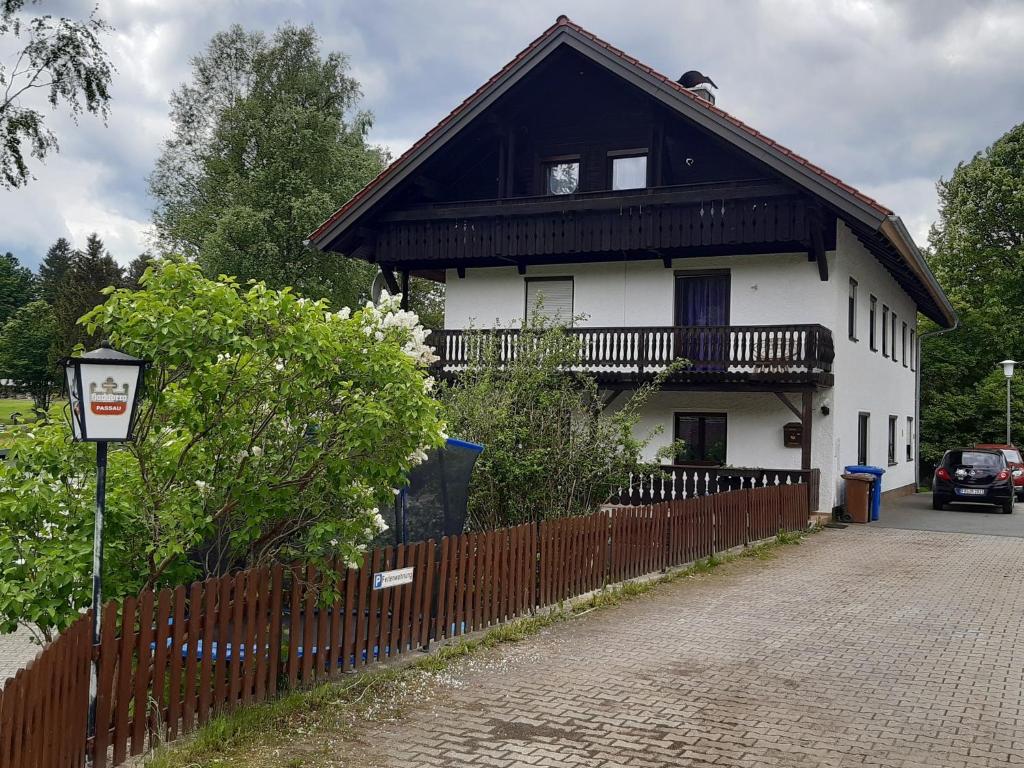 a white house with a black roof and a fence at AnNo - Wohlfühlen am Bachal in Neuschönau